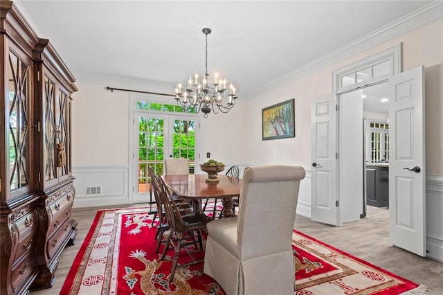 121 Clipper Bay Dr, Alpharetta, GA 30005 - dining space featuring a chandelier, ornamental molding, light wood-style flooring, wainscoting, and a decorative wall