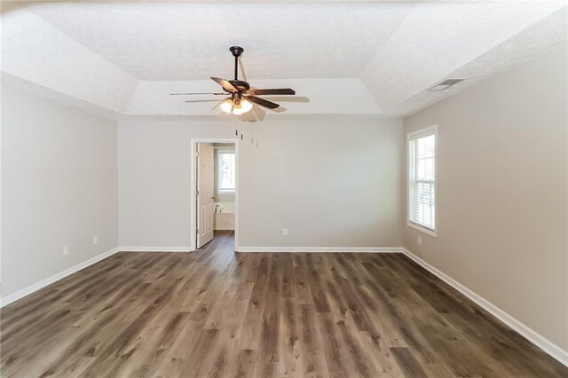 spare room featuring a textured ceiling, dark hardwood / wood-style flooring, a tray ceiling, and ceiling fan