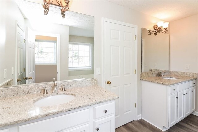 bathroom featuring hardwood / wood-style flooring, vanity, a textured ceiling, and an inviting chandelier