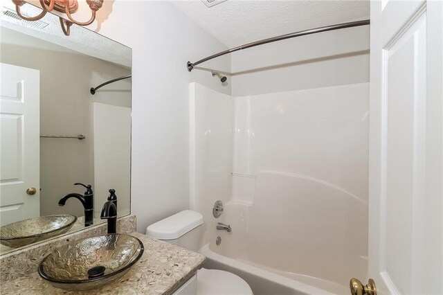 full bathroom with vanity,  shower combination, toilet, and a textured ceiling