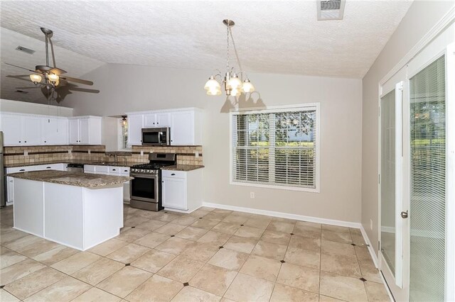 kitchen with decorative backsplash, a textured ceiling, stainless steel appliances, pendant lighting, and white cabinets