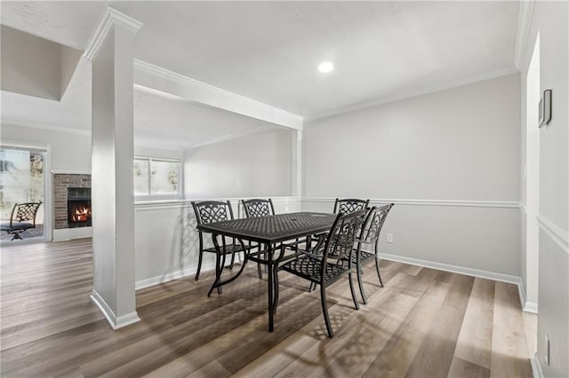 dining space with a fireplace, wood-type flooring, and crown molding