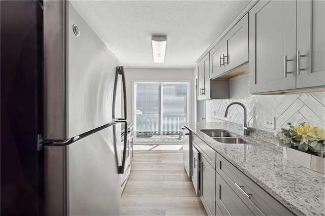 kitchen featuring light stone countertops, sink, tasteful backsplash, gray cabinets, and appliances with stainless steel finishes