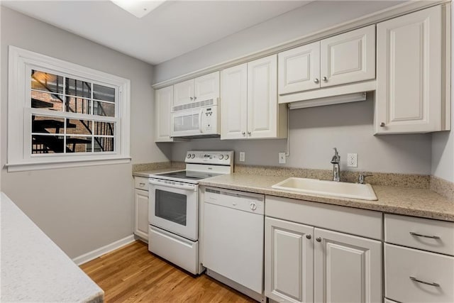 kitchen with light wood-style flooring, white appliances, a sink, white cabinetry, and light countertops