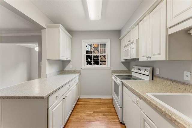 kitchen featuring white appliances, white cabinetry, light countertops, and a sink