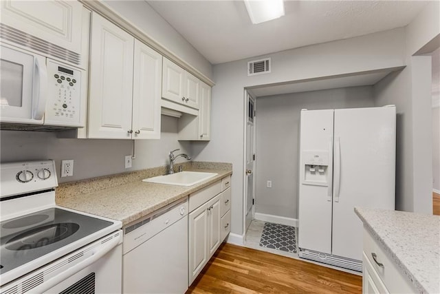 kitchen featuring light countertops, white appliances, a sink, and visible vents