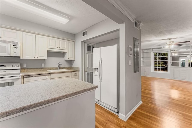 kitchen with white appliances, visible vents, light wood-style flooring, a textured ceiling, and a sink