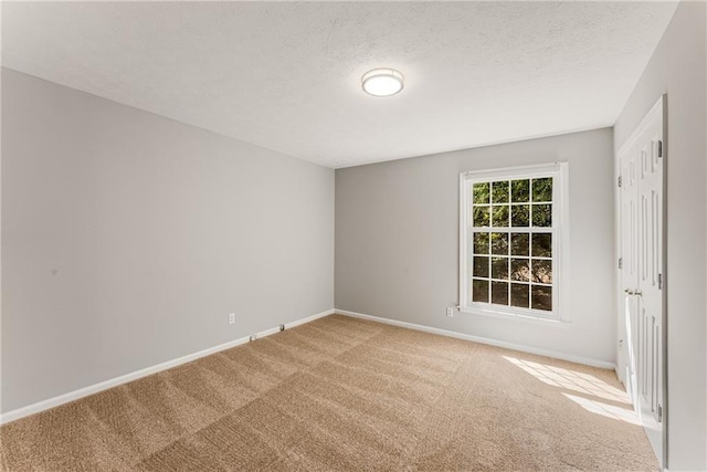 carpeted empty room with a textured ceiling and baseboards