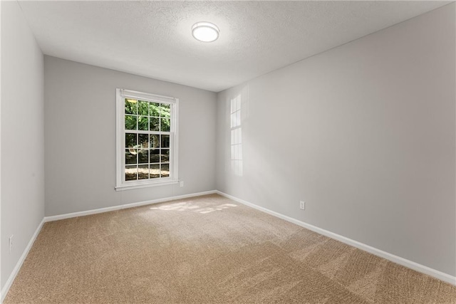 carpeted spare room featuring a textured ceiling and baseboards