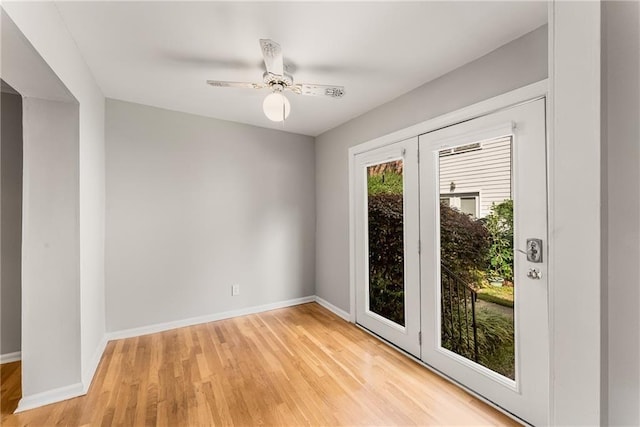 doorway with light wood-style floors, ceiling fan, and baseboards