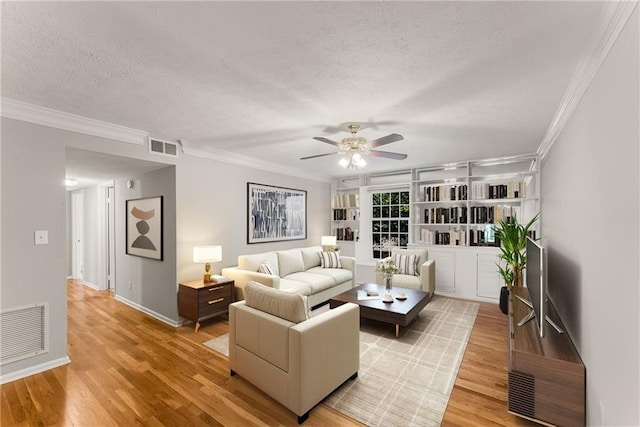 living room featuring light wood-type flooring, visible vents, and a textured ceiling