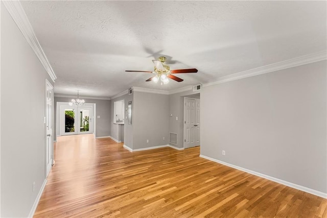 spare room featuring visible vents, ornamental molding, a textured ceiling, light wood-type flooring, and baseboards