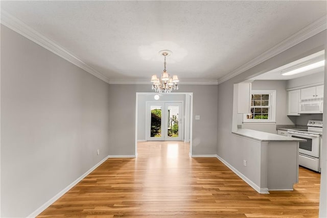 unfurnished dining area with baseboards, light wood-style flooring, ornamental molding, a textured ceiling, and a notable chandelier