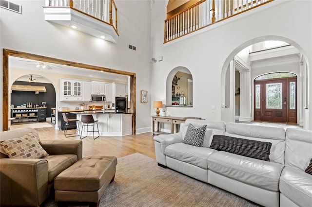 4337 Mountain View Rd, Oakwood, GA 30566 - living room featuring arched walkways, light wood-style flooring, a ceiling fan, and a high ceiling