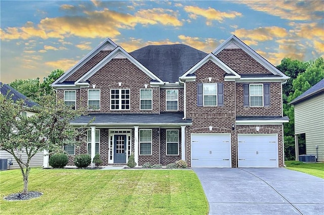 view of front of home featuring a garage, central air condition unit, and a lawn