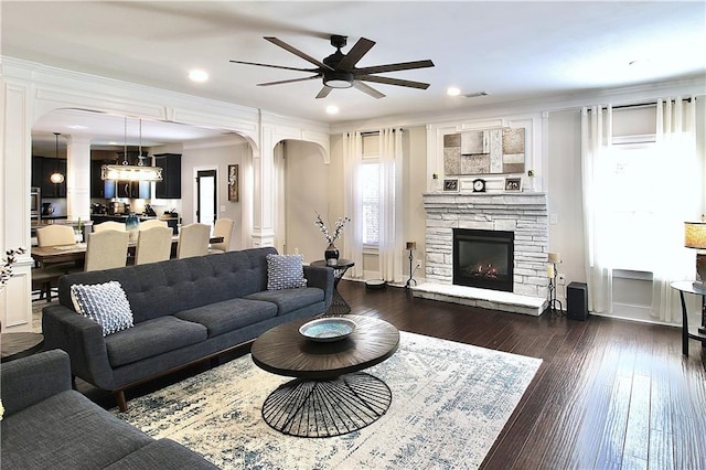 living room with ornamental molding, dark wood-type flooring, ceiling fan, and a fireplace