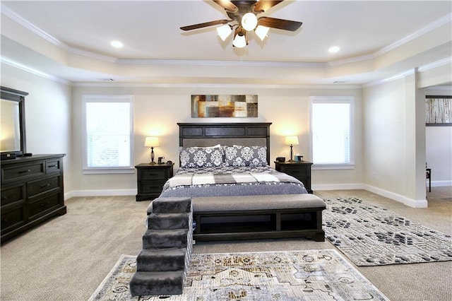 bedroom with light colored carpet, ceiling fan, and a tray ceiling