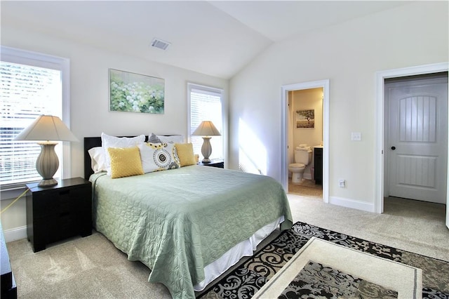 bedroom with lofted ceiling, connected bathroom, and light colored carpet