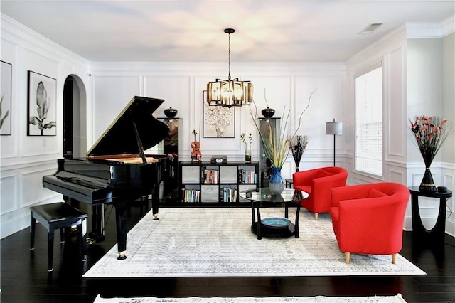 sitting room featuring dark wood-type flooring, crown molding, and a notable chandelier