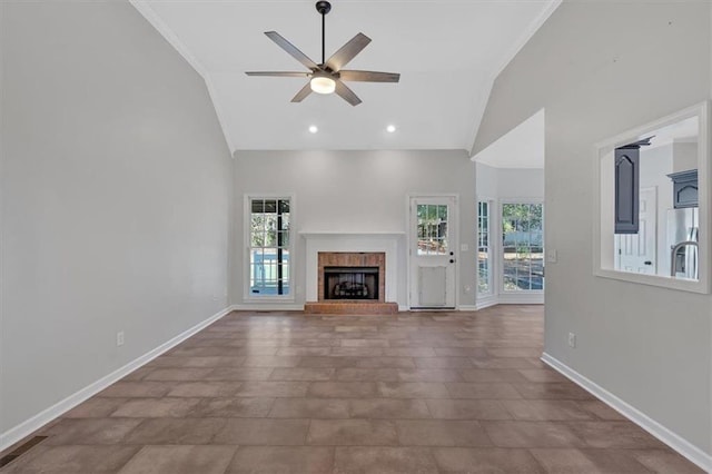unfurnished living room featuring ceiling fan, a brick fireplace, baseboards, high vaulted ceiling, and ornamental molding