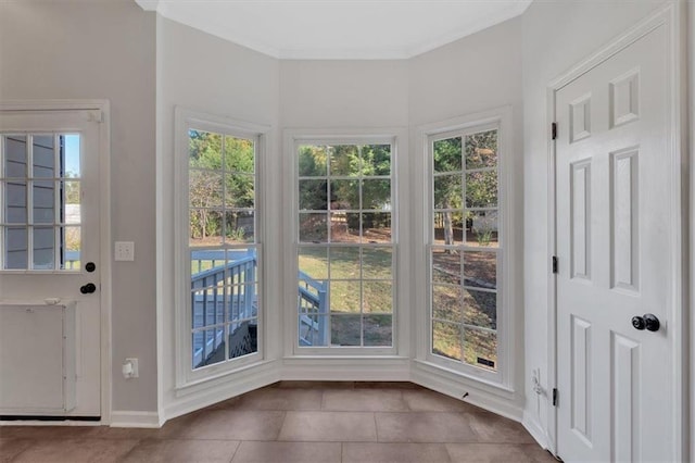 entryway with a healthy amount of sunlight, baseboards, ornamental molding, and tile patterned floors