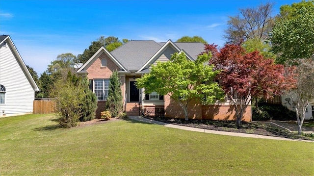 view of front facade with brick siding, fence, and a front yard
