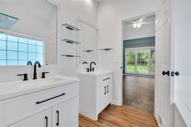 full bath with two vanities, a sink, and wood finished floors