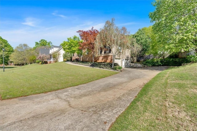 exterior space featuring concrete driveway and a front yard