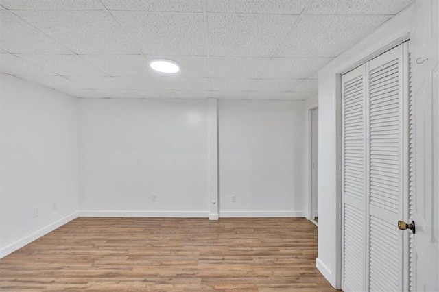 interior space featuring light wood-style floors, a paneled ceiling, baseboards, and a closet