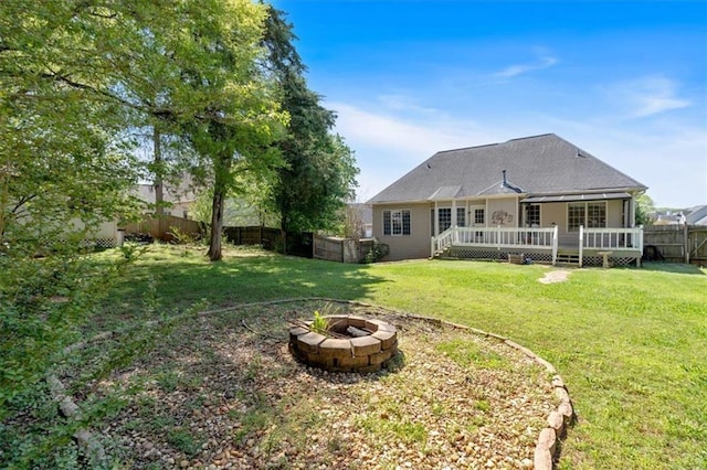 back of house featuring a fenced backyard, a lawn, an outdoor fire pit, and a deck