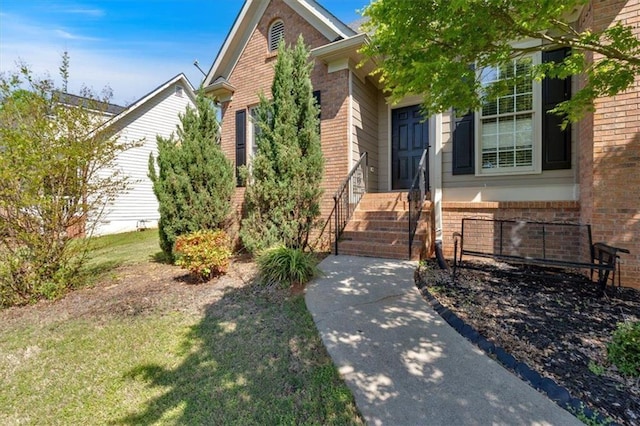 doorway to property with brick siding and a lawn