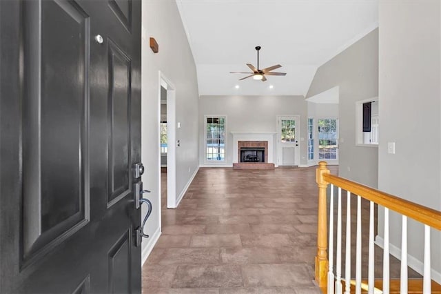 foyer entrance with ceiling fan, baseboards, lofted ceiling, and a fireplace