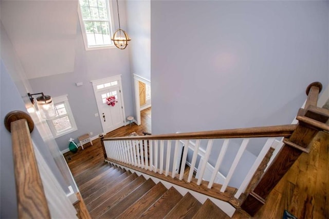 stairs featuring a high ceiling, hardwood / wood-style flooring, and a notable chandelier