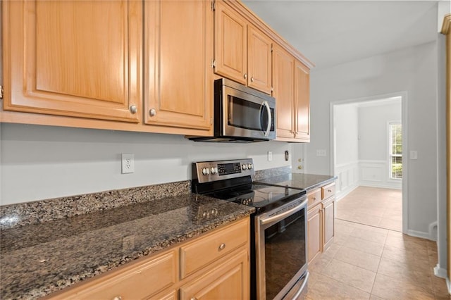 194 Lake Ruby Dr, Suwanee, GA 30024 - kitchen with appliances with stainless steel finishes, dark stone countertops, light tile patterned floors, a wainscoted wall, and a decorative wall