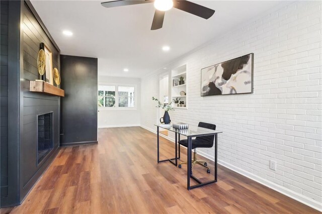 office area with ceiling fan, dark wood-type flooring, and brick wall