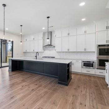 6450 Pond View Dr, Cumming, GA 30028 - kitchen with wall chimney range hood, appliances with stainless steel finishes, a sink, white cabinetry, and recessed lighting