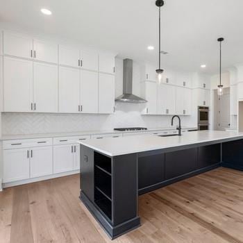 6450 Pond View Dr, Cumming, GA 30028 - kitchen featuring wall chimney exhaust hood, a sink, double oven, white cabinets, and light countertops