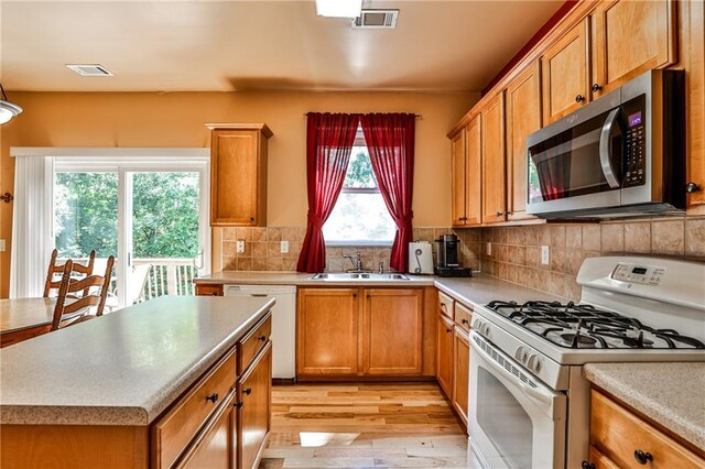 kitchen featuring light hardwood / wood-style flooring, white appliances, sink, and backsplash