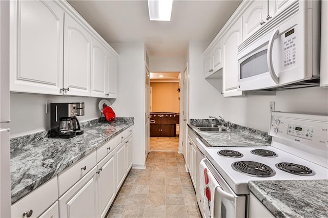 kitchen with white appliances, white cabinetry, dark stone counters, light tile patterned floors, and sink