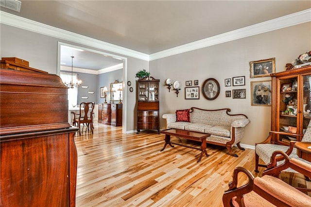 living room featuring light wood-type flooring, a chandelier, and ornamental molding