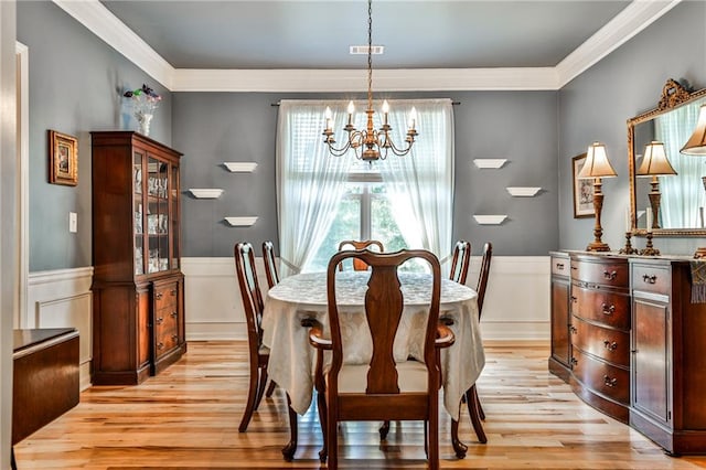 dining room with a notable chandelier, ornamental molding, and light hardwood / wood-style floors