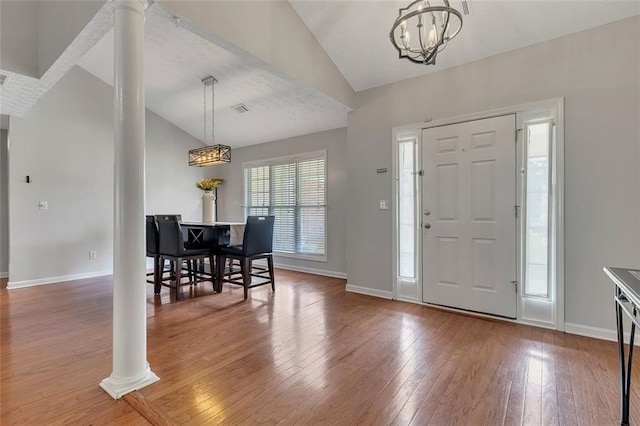 964 Natural Brook Trl, Lawrenceville, GA 30045 - foyer entrance featuring lofted ceiling, a chandelier, decorative columns, hardwood / wood-style flooring, and a textured ceiling