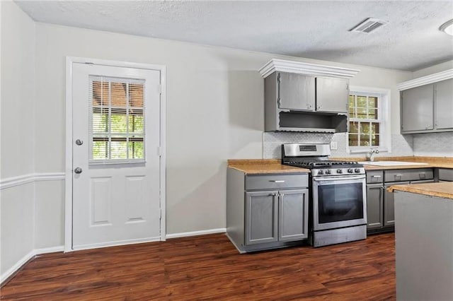 kitchen with backsplash, stainless steel gas range oven, gray cabinetry, and a healthy amount of sunlight