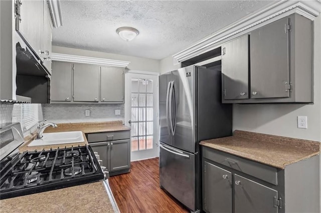 kitchen with gas stove, stainless steel refrigerator, gray cabinetry, and sink