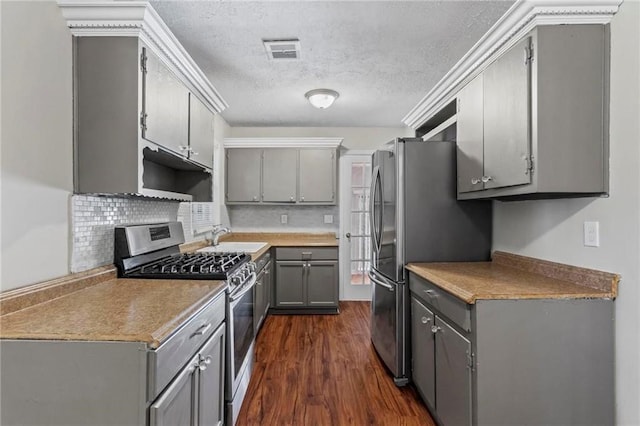 kitchen with appliances with stainless steel finishes, gray cabinetry, a textured ceiling, dark wood-type flooring, and sink