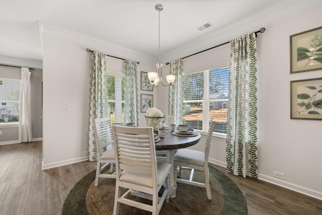 dining area featuring ornamental molding, dark wood-type flooring, and an inviting chandelier