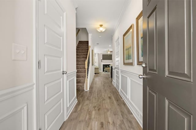 hallway featuring crown molding and light hardwood / wood-style flooring