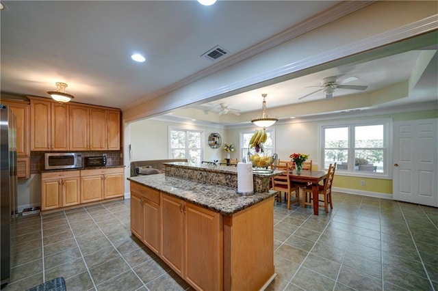 3265 Bethesda Park Ct, Lawrenceville, GA 30044 - kitchen with crown molding, ceiling fan, tile patterned flooring, dark stone counters, and a center island