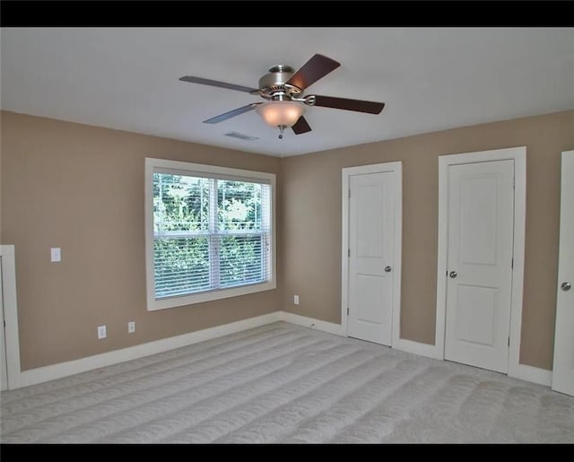 unfurnished bedroom featuring visible vents, baseboards, ceiling fan, and light colored carpet