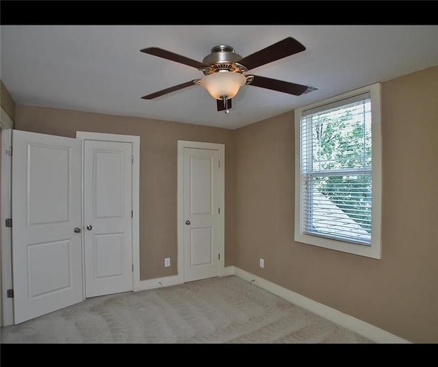unfurnished bedroom featuring light carpet, baseboards, and a ceiling fan